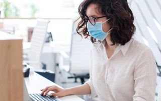 woman working on computer with mask on